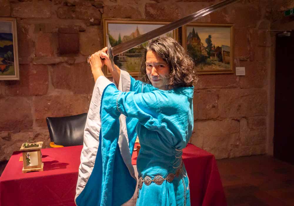 Die mittelalterlich gewandete Autorin demonstriert dem Publikum eine Schwertübung